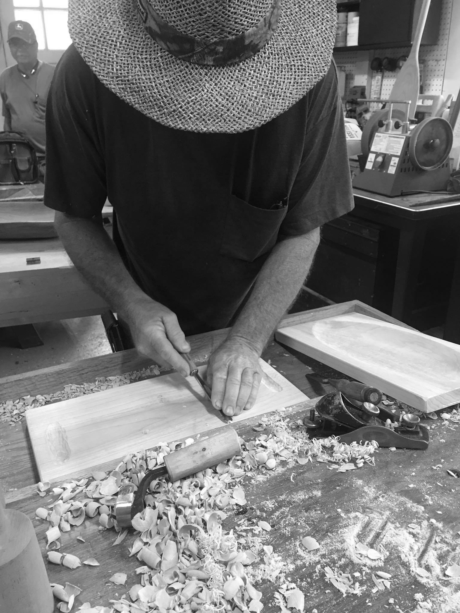 man with hand tools working in shop on a wooden piece