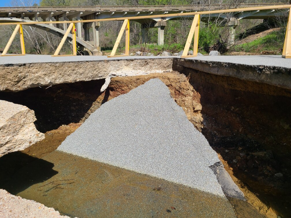 A closeup of a piece of grey asphault from a roadway that collapsed into a clear stream.