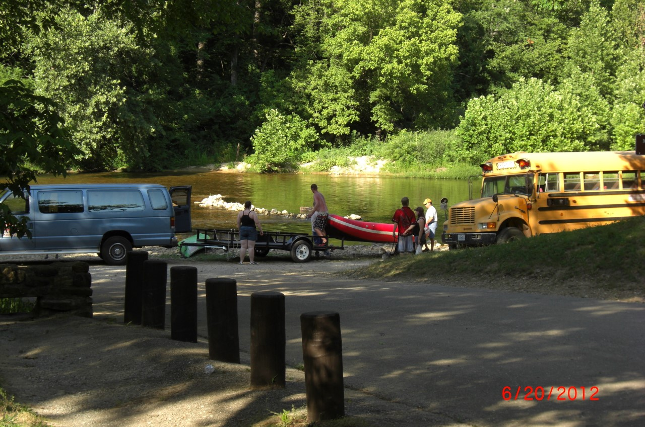 people on gravel bar putting in kayaks, rafts by clear river