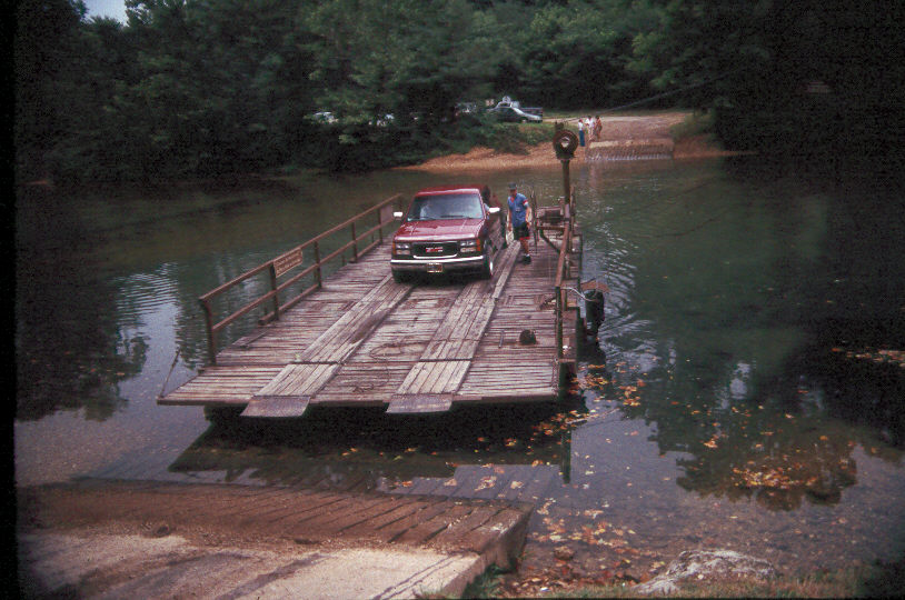 downloadffffjj An iron and wood river ferry with a car and man cross the small current river