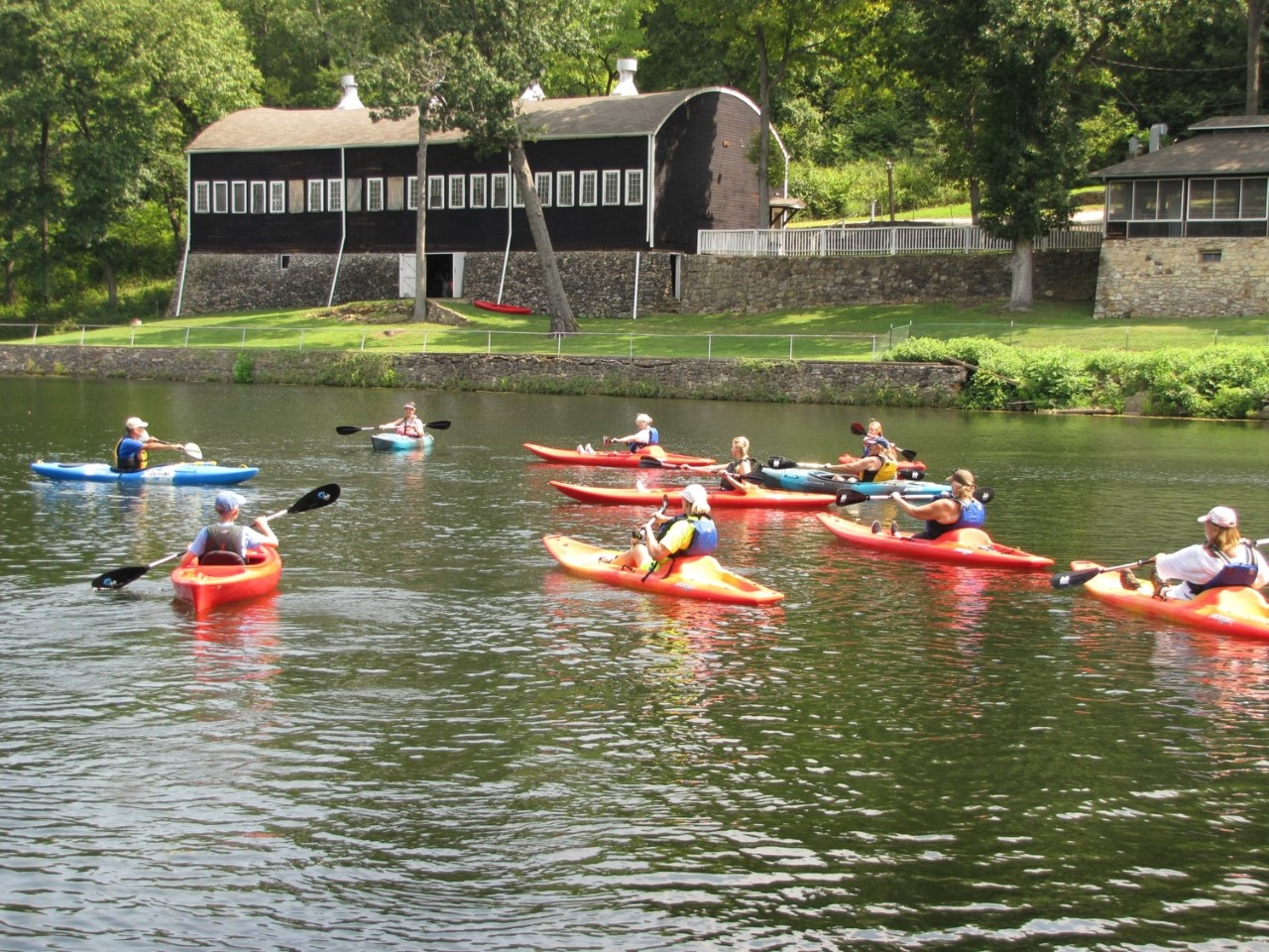 a group of paddlers in kayaks on the lake with brown buildings in the background
