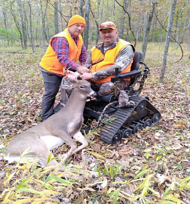 downloadq132455 A hunter in a powered wheelchair holding his trophy buck after a successful hunt