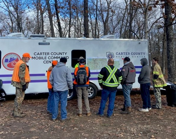 downloadrescue A group of rescue workers in front of a moblile command unit in the woods during a search and rescue