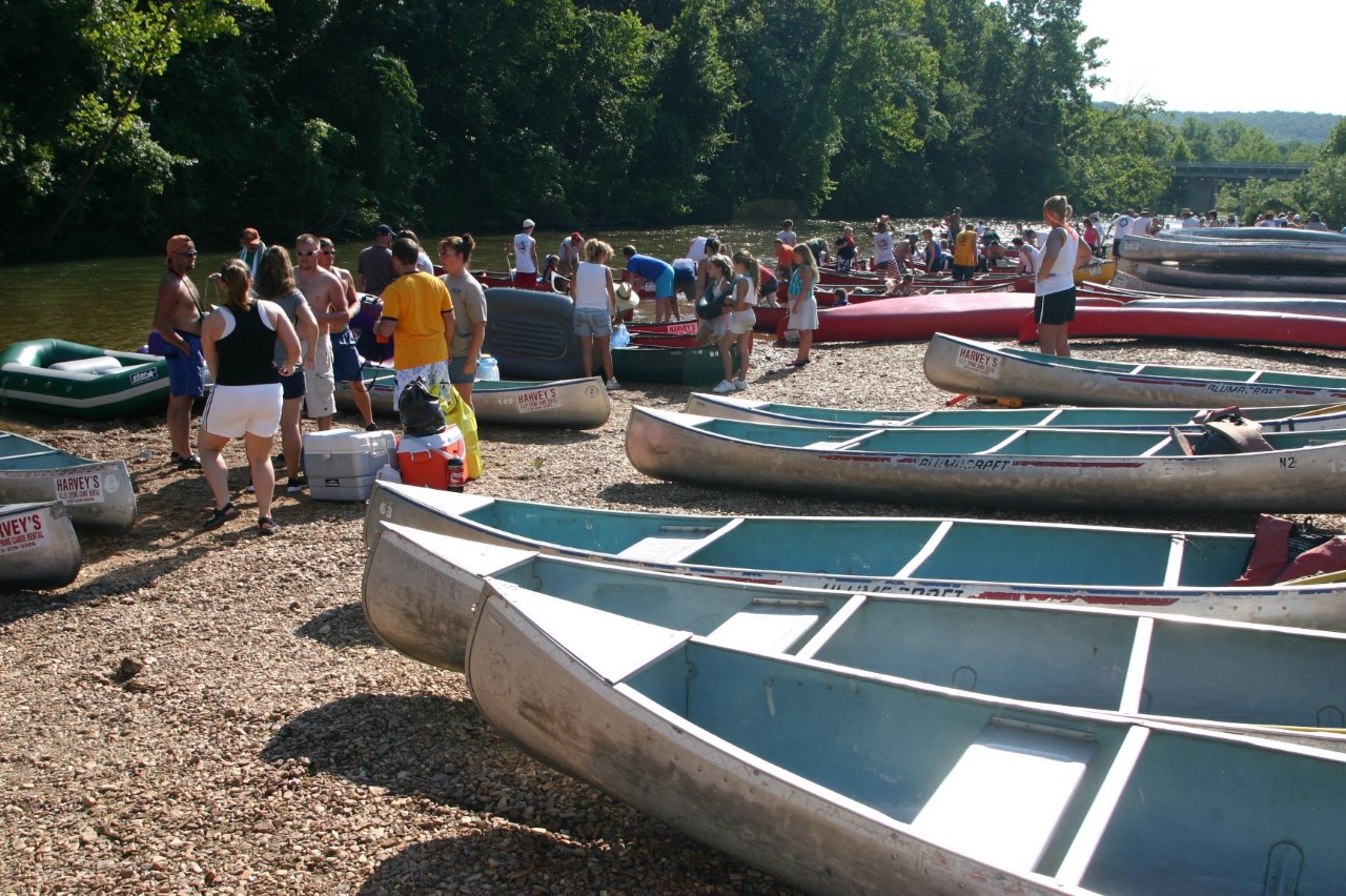 aluminum canoes on riverbank with floaters waiting to depart
