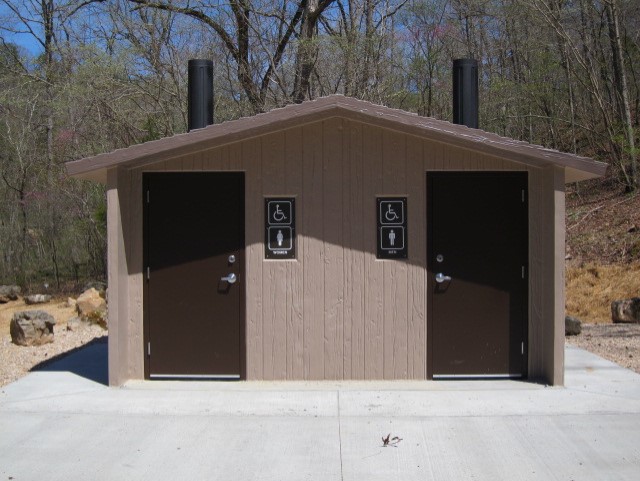 thumbnail_Buck Hollow vault toilet A close up view of a beige concrete two sided restroom with concrete pad and chimneys coming out the top