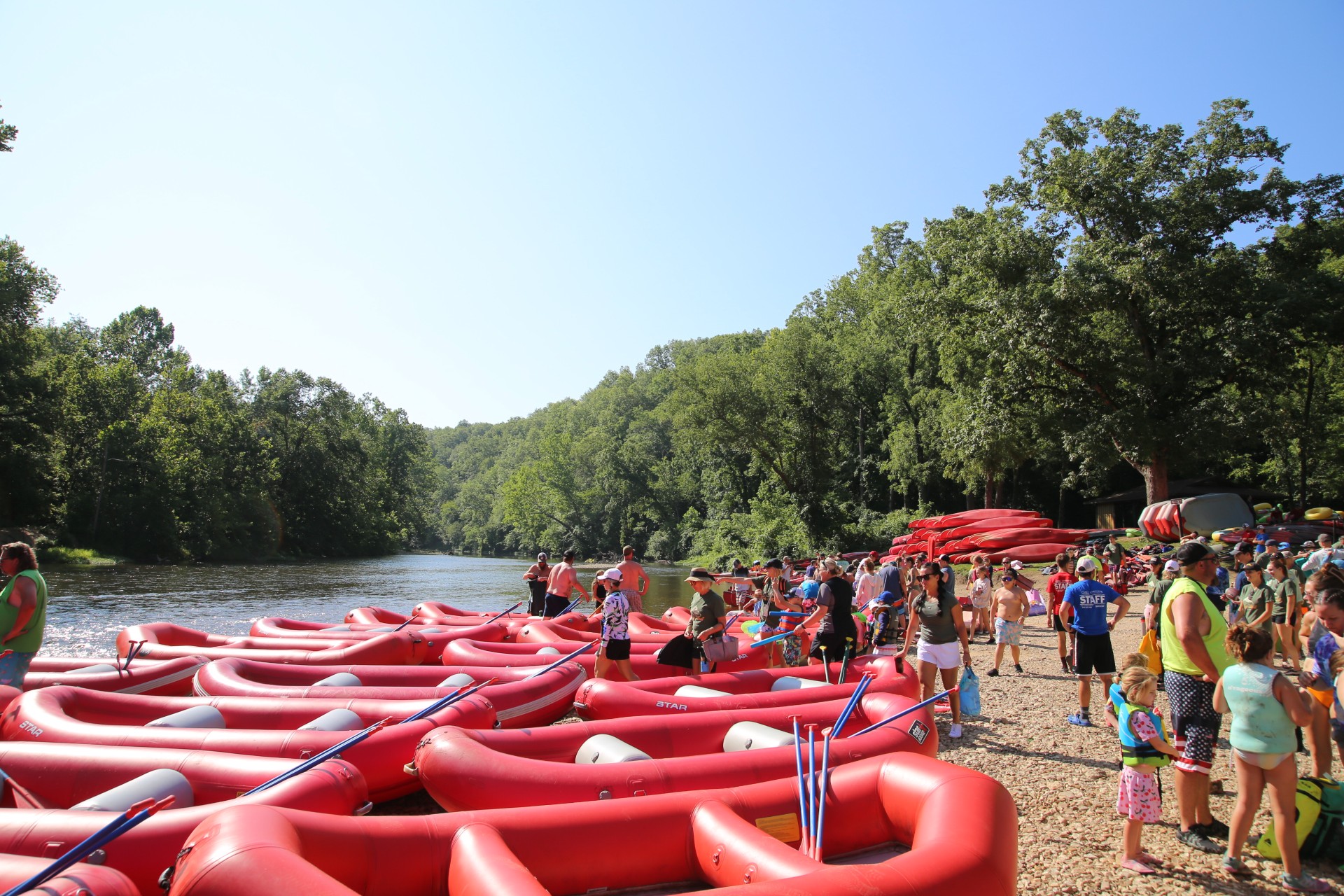 thumbnail_IMG_1047 A busy gravel bar by the river. Red rafts and kayaks are piled up with visitors of all ages waiting to load in them and float.
