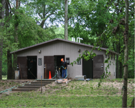 Man with hose cleaning restroom building