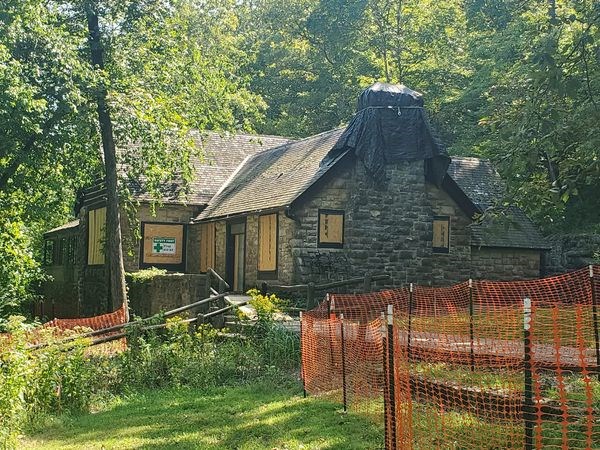 Big Spring Lodge. A large stone and wood structure with plywood in the windows and orange safety fence surrouding during construction