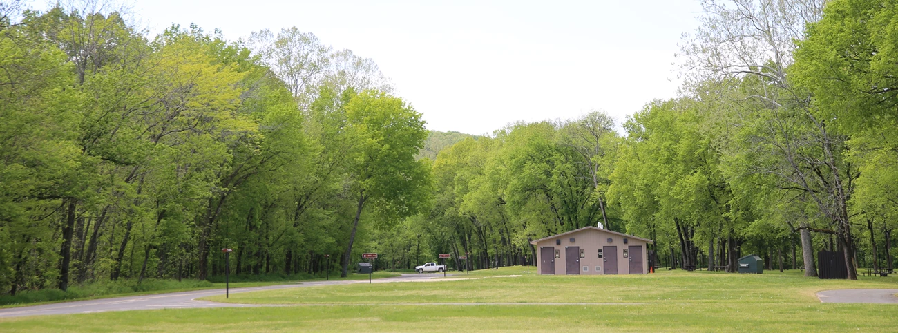Developed Campground der Ozark National Scenic Riverways mit Wiese, Bäumen und Sanitärgebäude