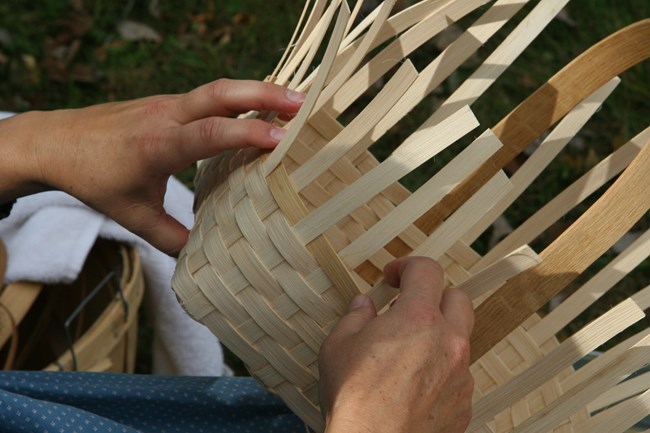 hands weaving an oak basket up close