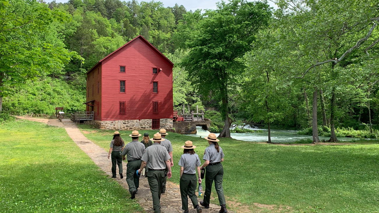 A group of park rangers walk towards Alley Mill.