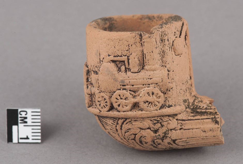 Close up of a ceramic tobacco pipe bowl with a locomotive on it.