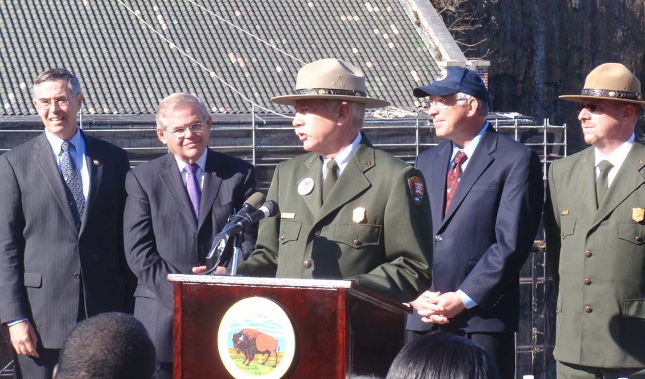 Jon Jarvis, Director of the National Park Service (center) speaks to a gathered crowd as other dignitaries listen at the Paterson Great Falls NHP establishment ceremony on 11/7/2011. From left to right: Congressman Rush Holt, Senator Bob Menendez, Directo