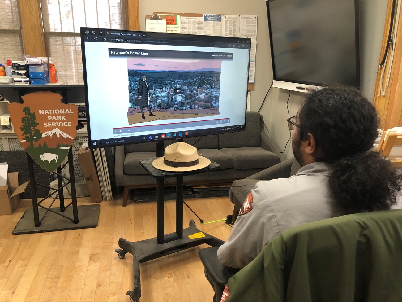 A park ranger watches a video on "Paterson's Power Lines" on a television in an office