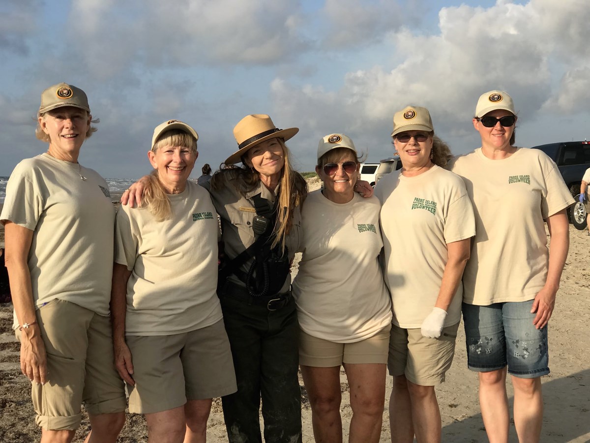 Volunteers with Dr. Shaver linking arms and smiling after a Kemp's ridley hatchling release.