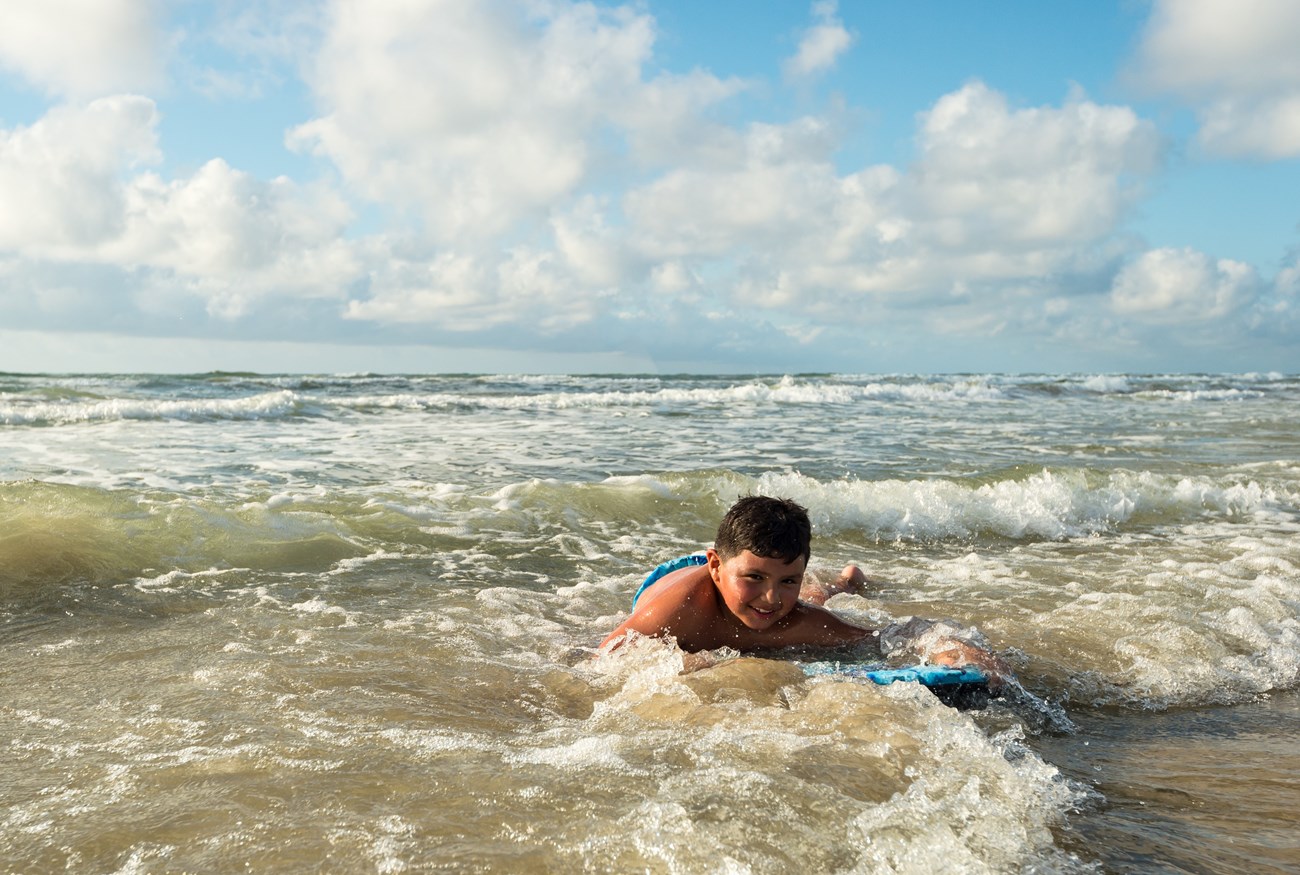A child rides a bodyboard in the surf.