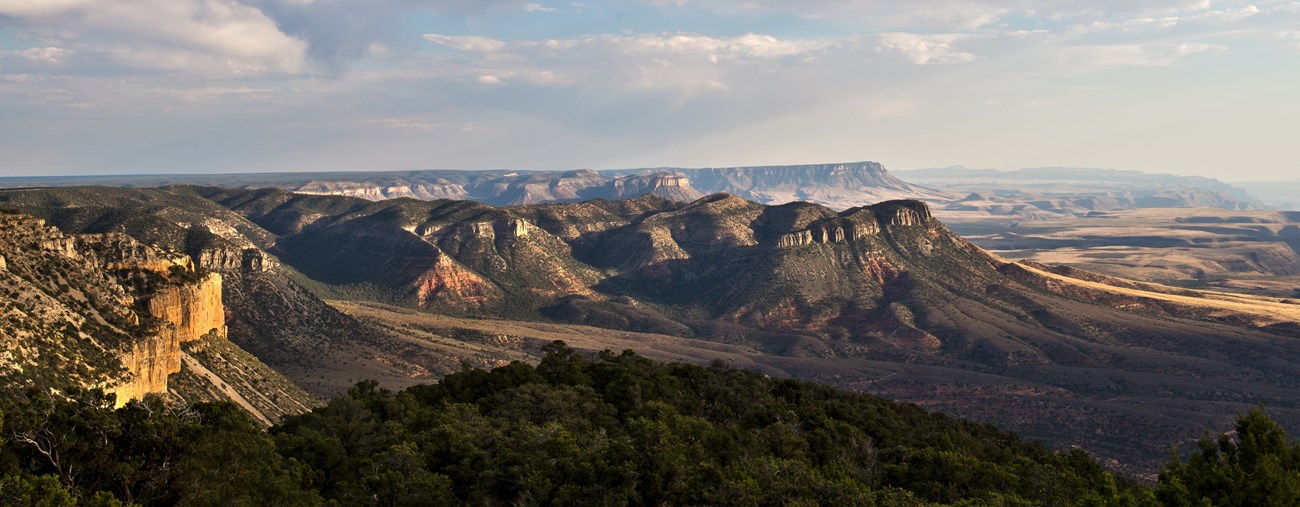 Ridgeline of mesas lit by the setting sun. An expansive landscape view looking out across the monument of Hudson Point.