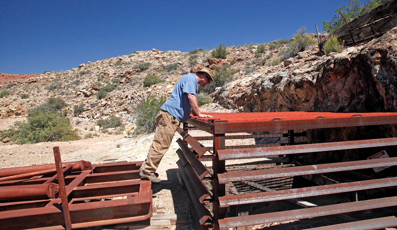 Person looking into Copper Mountain mine shaft in Parashant Canyon Copper Mountain Mine shaft and steel gate