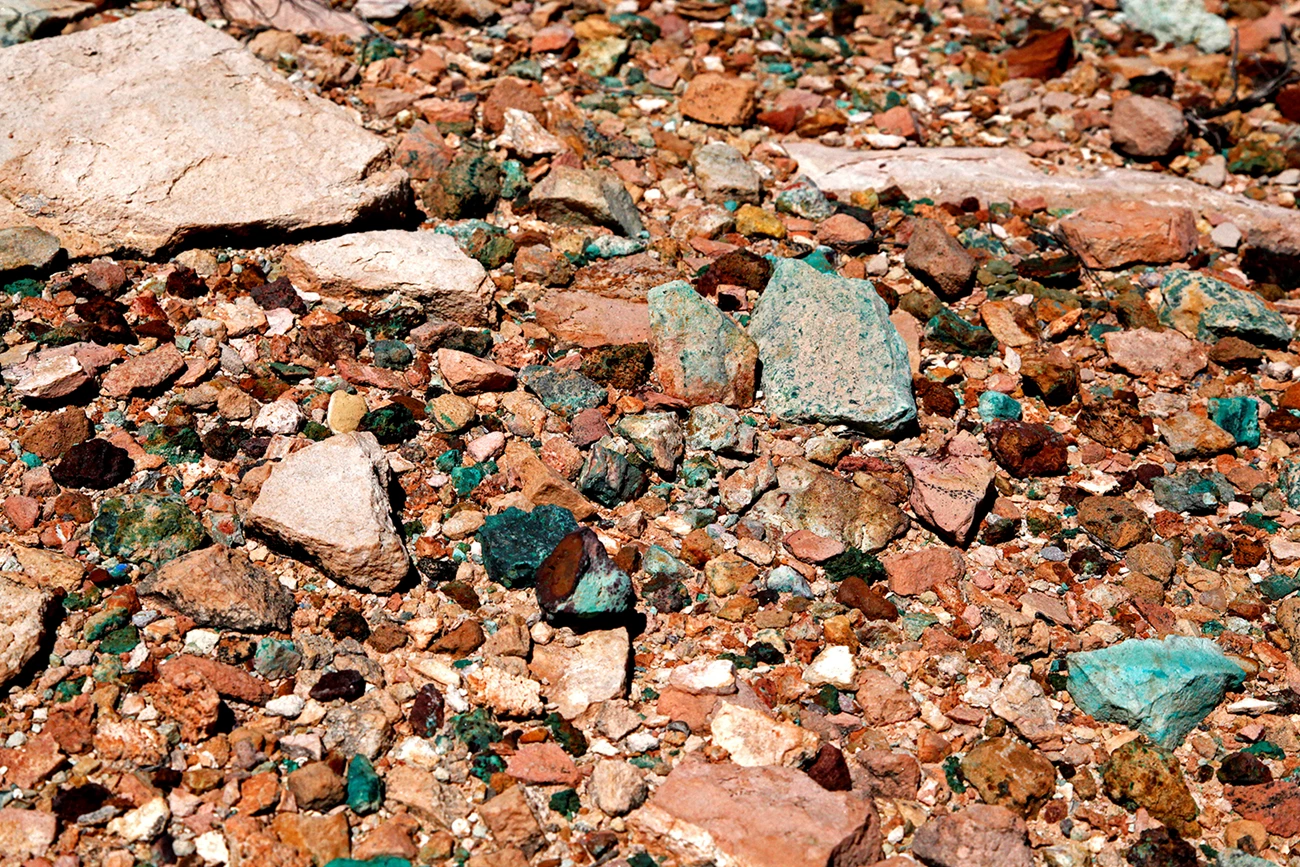 Copper ore rocks on the ground. Green are malachite, small blue pieces are azurite. Assortment of broken rocks on the ground including blue and green color rocks that are copper ore