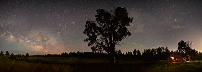 Light in the windows of Waring Ranch set against a Milky Way sky.