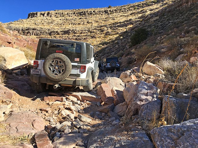 Two jeeps in a rocky canyon driving across boulders