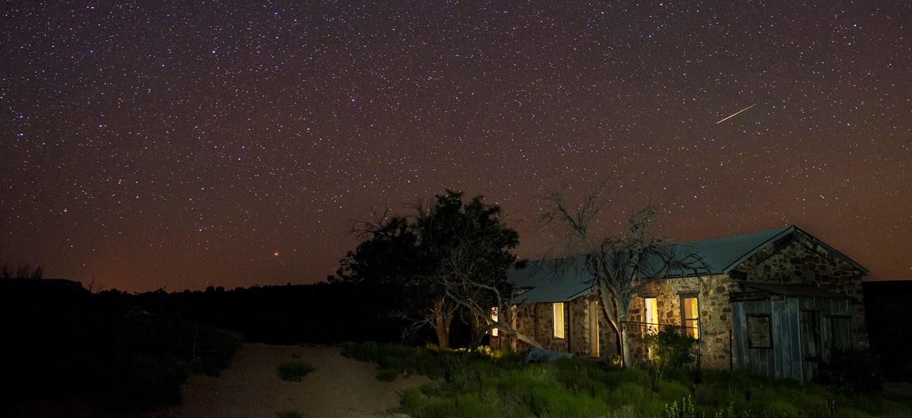 Stars and a shooting star above the historic bunkhouse ruin