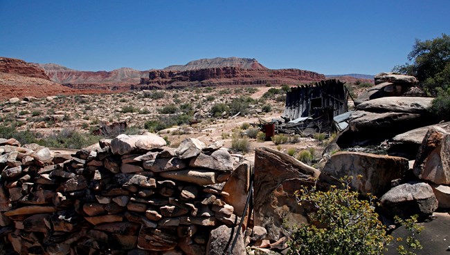 Stone wall and building that is mostly collapsed with cliffs in the distance