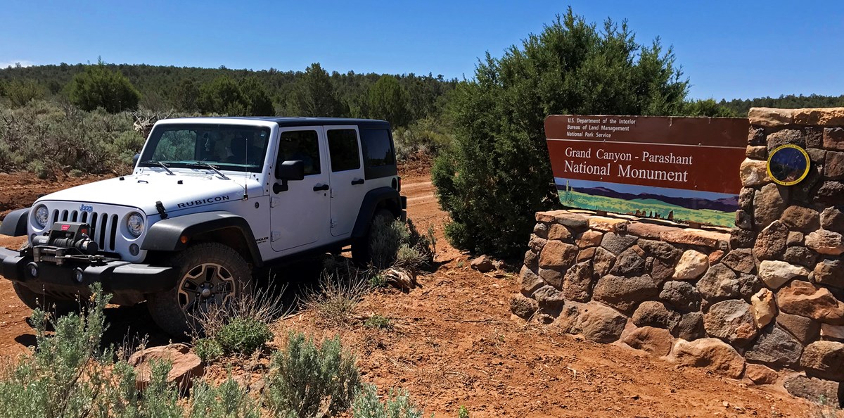 Jeep at monument entrance sign Jeep at monument entrance sign