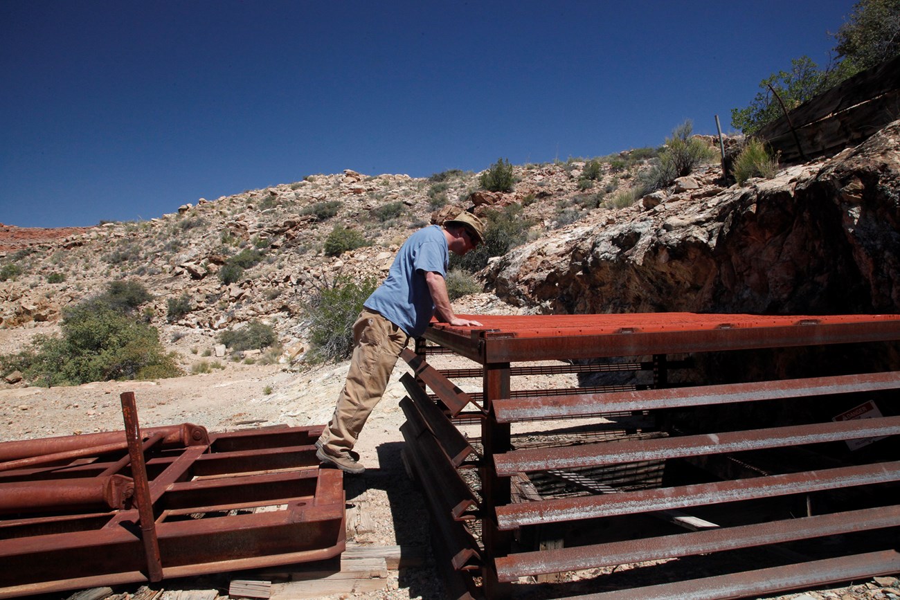 Visitor looking through steel grate down into the mine