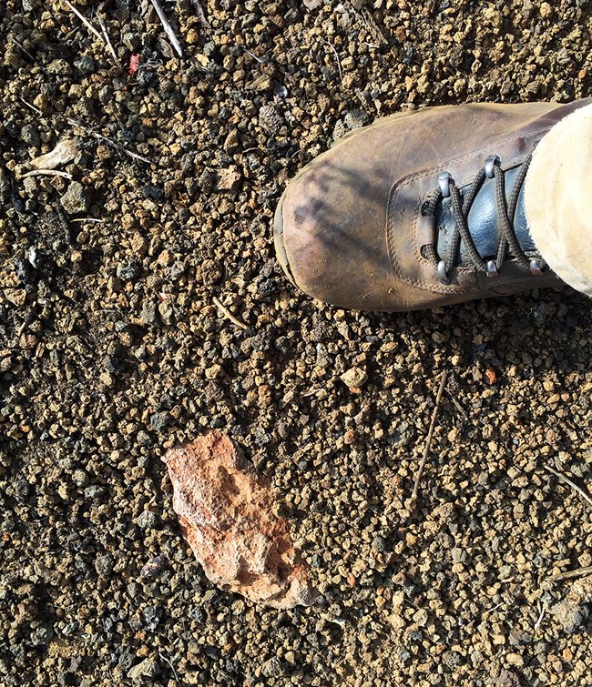 pebbles of volcanic scoria and a hiking boot for scale