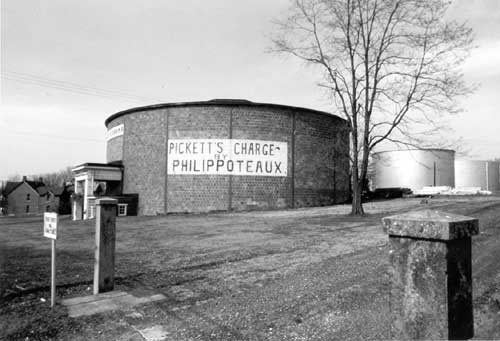 Visitor Center and Cyclorama Building: showing rounded brick building that said "PICKETT'S CHARGE- FLY PHILIPPOTEAUX with two metal tanks in the background.