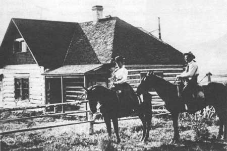horseback riders in front of homestead