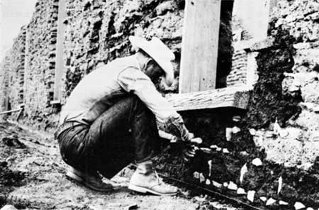 workman shoring up weak wall of adobe barracks