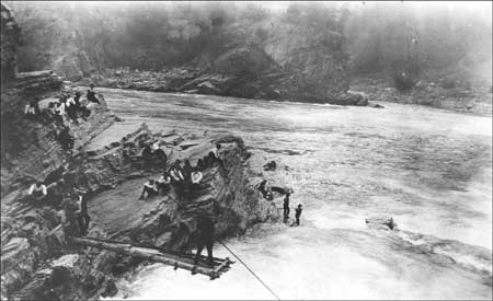 Indians fishing from platform and rocks at Kettle Falls