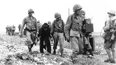 two Marines help an aged Okinawan to safety