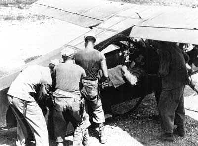 Navy corpsmen lifting a wounded Marine into an airplane