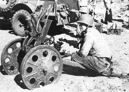 Marine examines Japanese 70mm howitzer