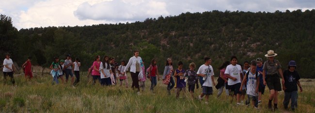 Large school group hiking to site with ranger leading Large school group hiking to site with ranger leading