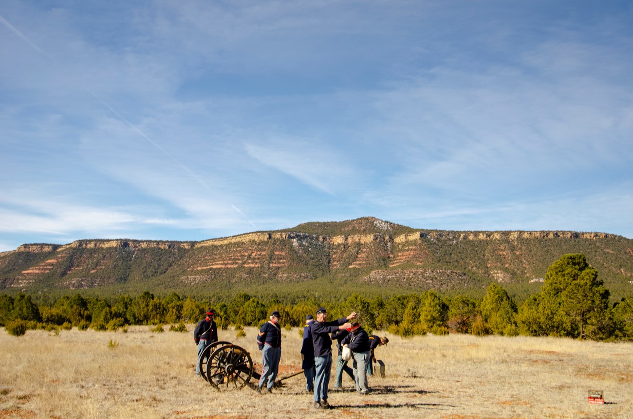 Men dressed in Civil War uniforms with canyons and Glorieta Mesa in the background