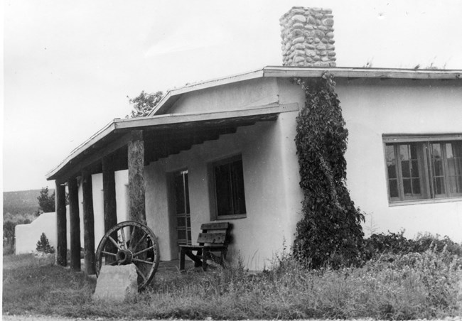 One story building with bench and wagon will under porch.
