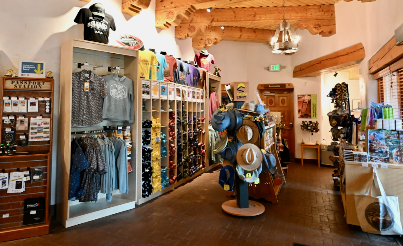 Store with shelves holding shirts and passport memorabilia, a hat rack, other items.