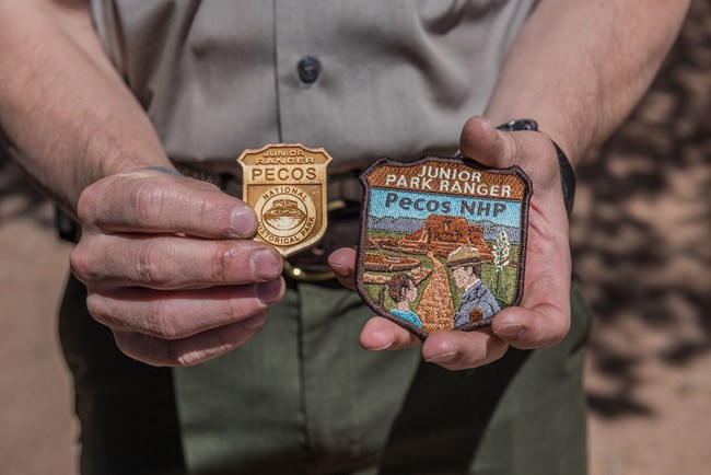 Junior Ranger Patch and Badge wooden badge and patch held in park rangers hands