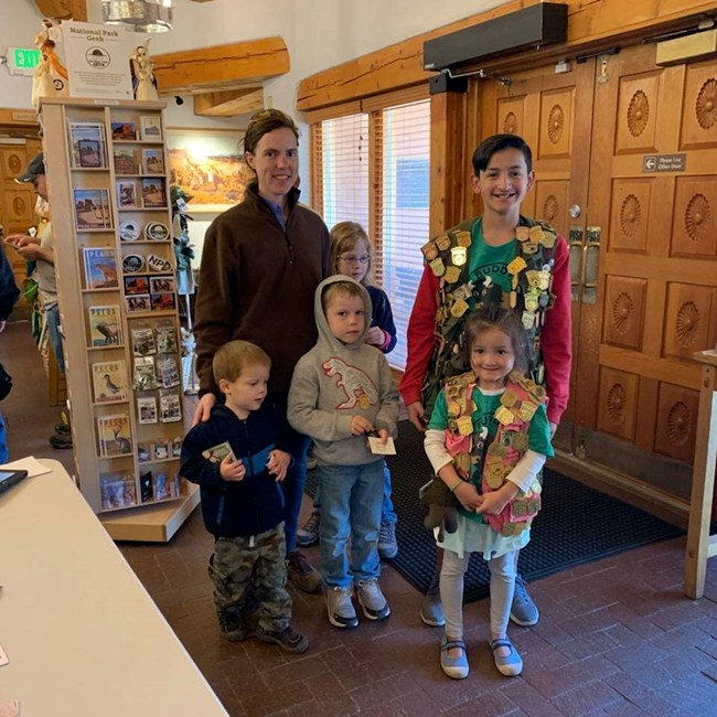 A family gathered for a photo with junior ranger vests on.