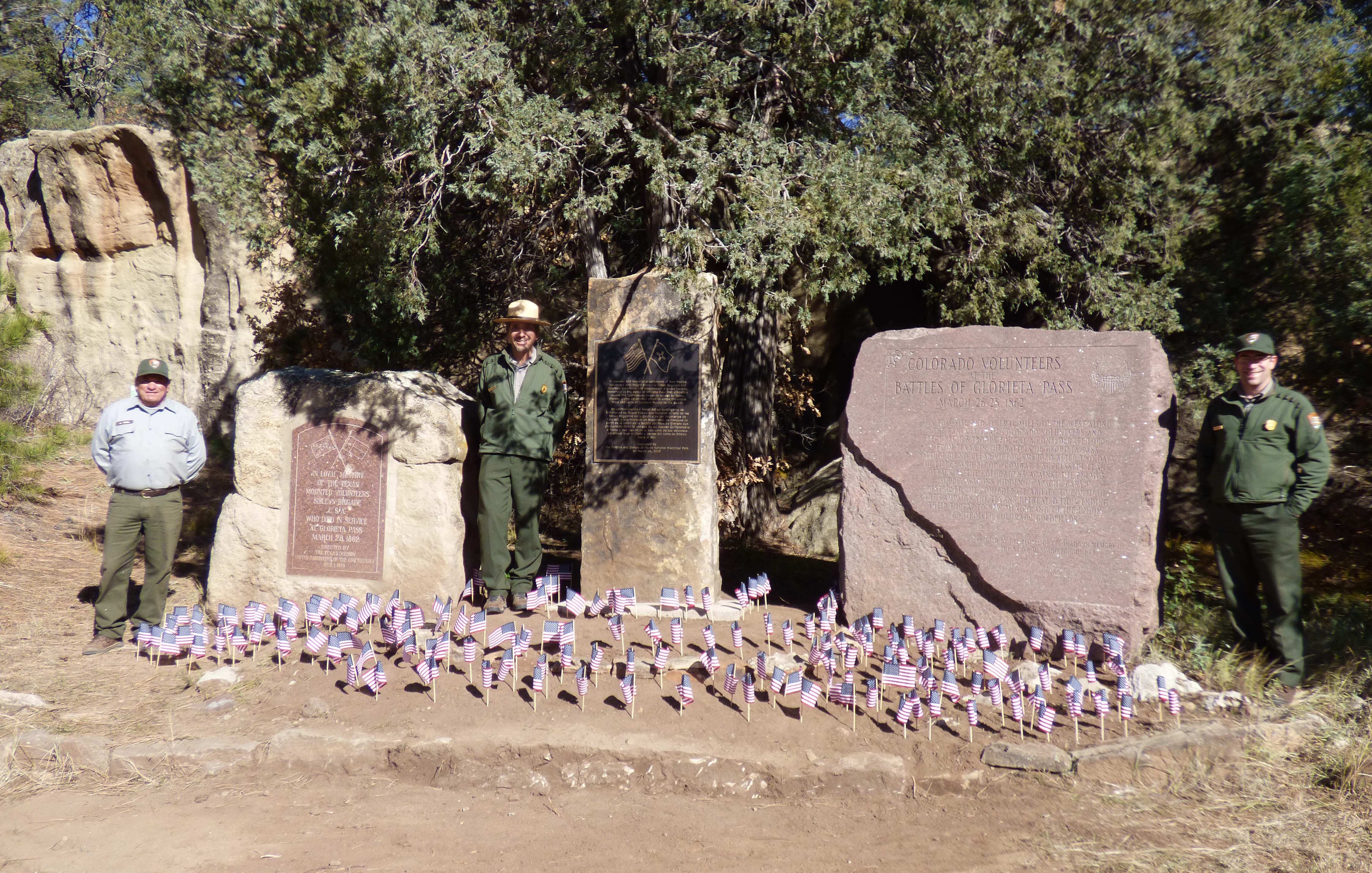 American flags around stone monuments with rangers in between monuments.