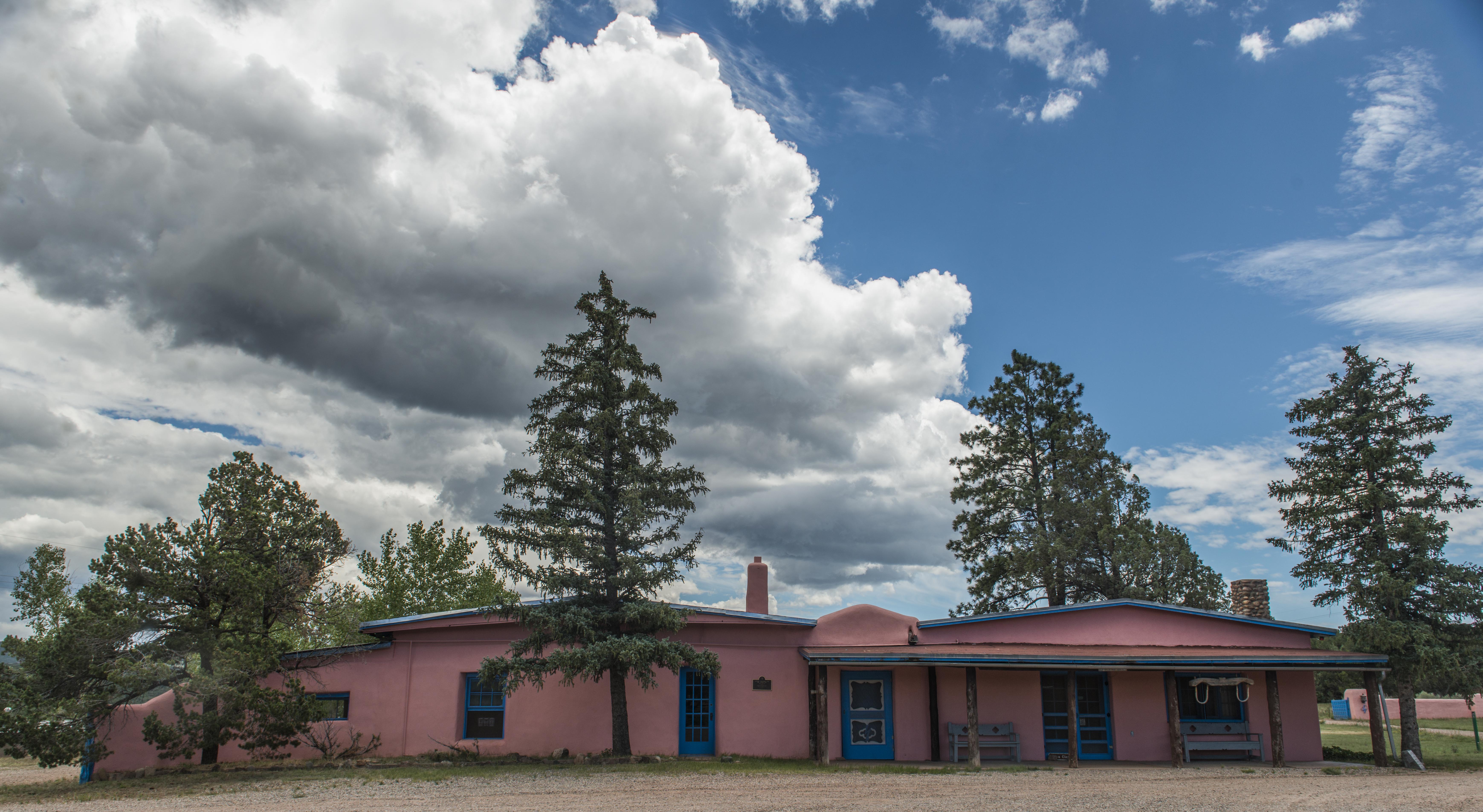 A pink building surrounded by trees and a cloudy sky.