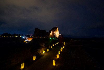 The remains of an old Spanish mission church with lighted lanterns leading to the building.