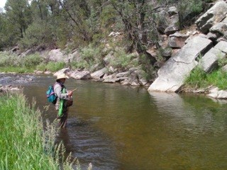 An angler stands by the river.