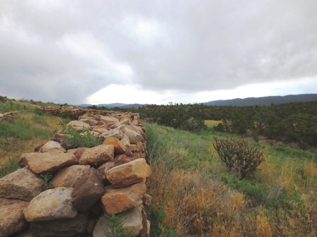 Looking along low rock wall under cloudy sky Looking along low rock wall under cloudy sky