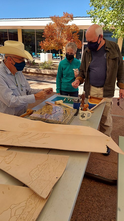 Artist demonstrates with punches, pigment and pieces of leather for visitors