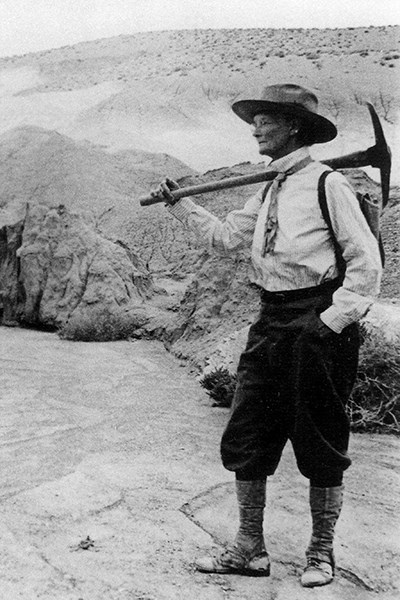 Woman with pick axe over her shoulder in old photo